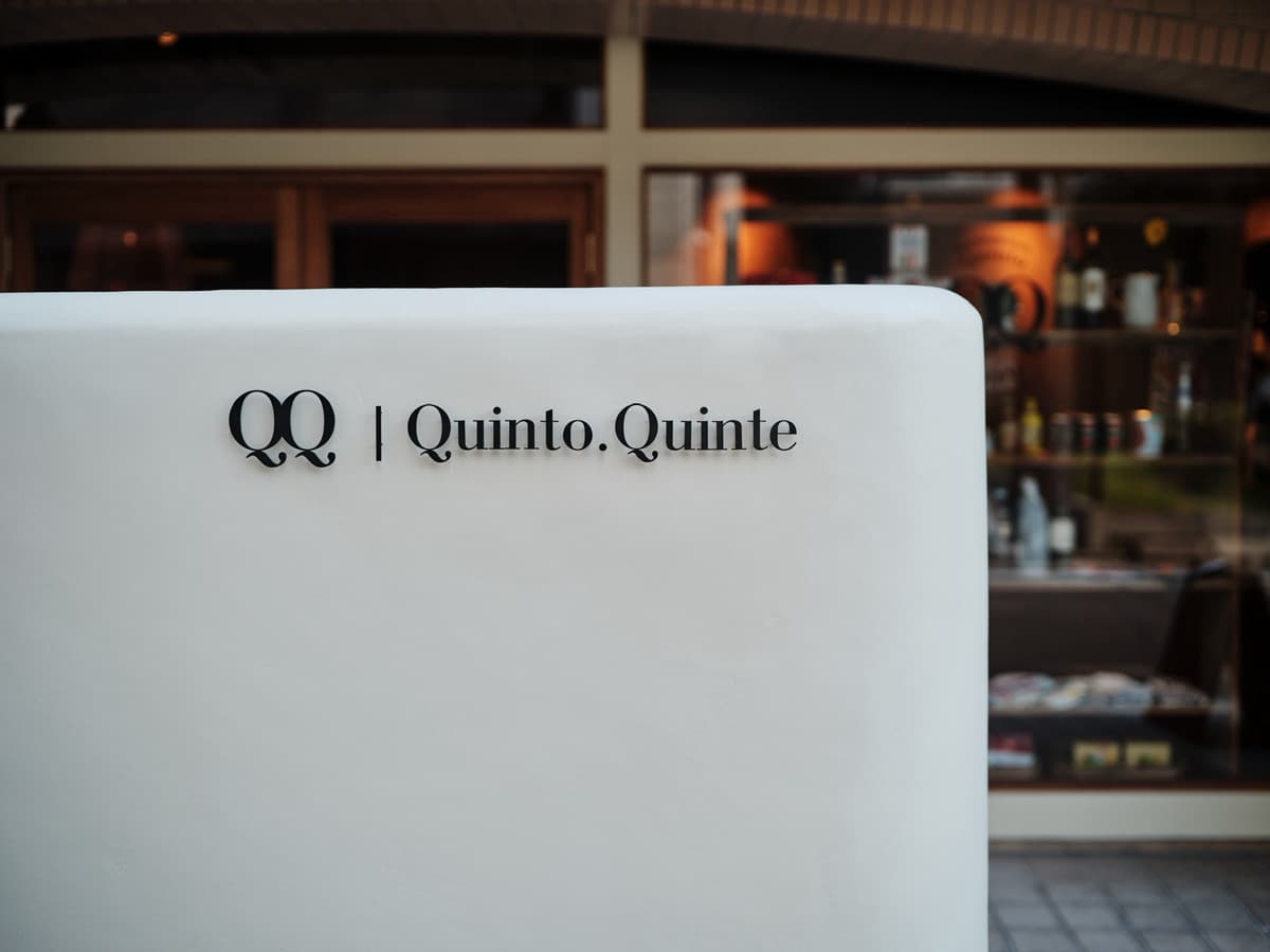 白い壁に掲げたQQ Quinto.Quinteの看板